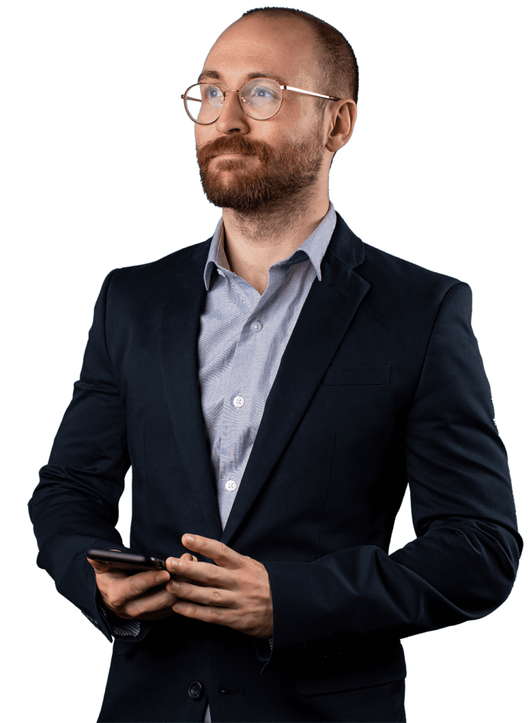 A bearded man with glasses in a suit holds a smartphone, looking upward.